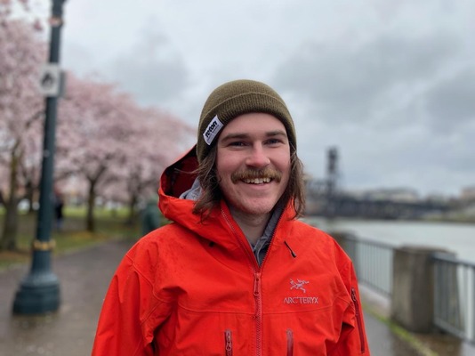 A picture of the author on a rainy day surrounded by cherry blossom trees